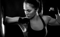 Studio shot of female boxer punching a boxing bag, Black and white.